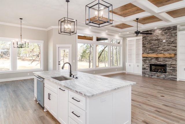 kitchen featuring a kitchen island with sink, decorative light fixtures, light stone countertops, and white cabinets