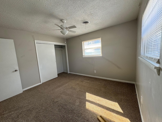 unfurnished bedroom featuring ceiling fan, carpet floors, a closet, and a textured ceiling