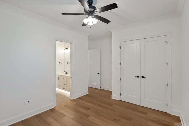 unfurnished bedroom with ornamental molding, ceiling fan, light wood-type flooring, and a closet