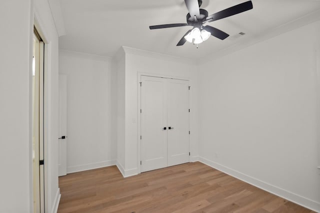 unfurnished bedroom featuring crown molding, ceiling fan, light hardwood / wood-style floors, and a closet