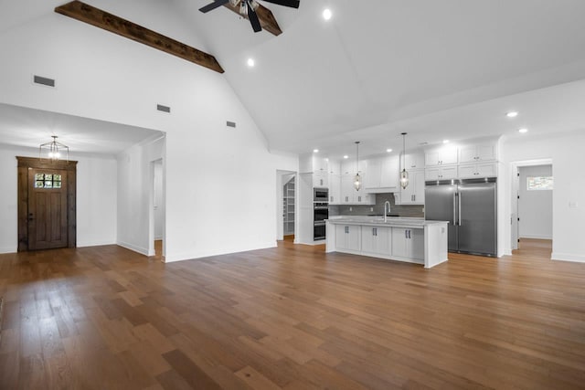 unfurnished living room featuring ceiling fan with notable chandelier, high vaulted ceiling, sink, dark hardwood / wood-style flooring, and beam ceiling