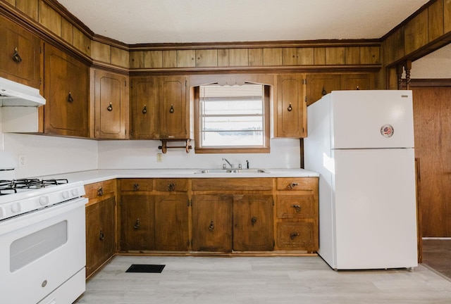 kitchen featuring sink, white appliances, and light wood-type flooring