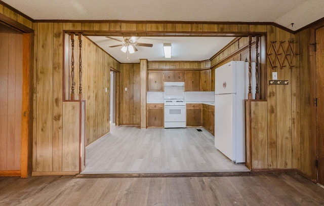 kitchen featuring white appliances, ornamental molding, wooden walls, and light hardwood / wood-style flooring