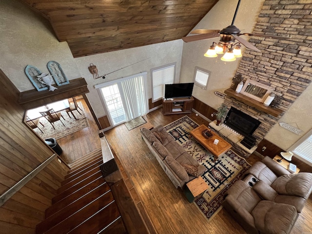 living room featuring a stone fireplace, high vaulted ceiling, wood ceiling, ceiling fan, and dark wood-type flooring