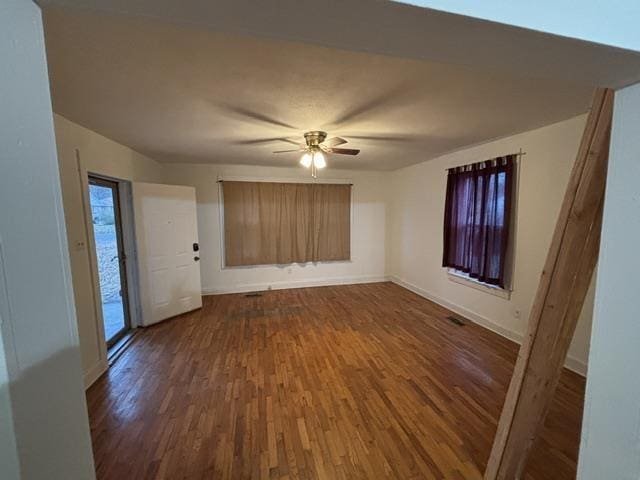 unfurnished living room with dark hardwood / wood-style flooring and ceiling fan