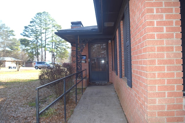 doorway to property with brick siding and a chimney