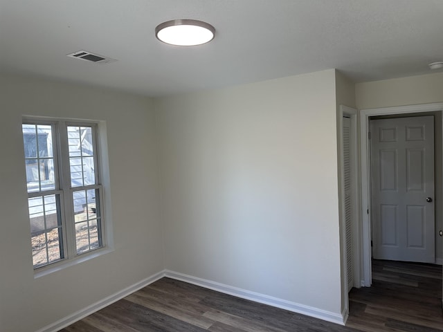 empty room with dark hardwood / wood-style flooring and plenty of natural light