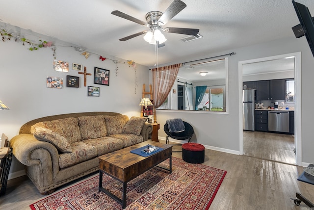 living room with dark hardwood / wood-style floors, a textured ceiling, and ceiling fan