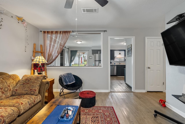 living room with ceiling fan, sink, and light hardwood / wood-style flooring