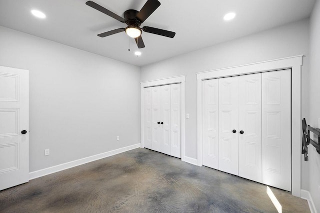 unfurnished bedroom with ceiling fan and two closets