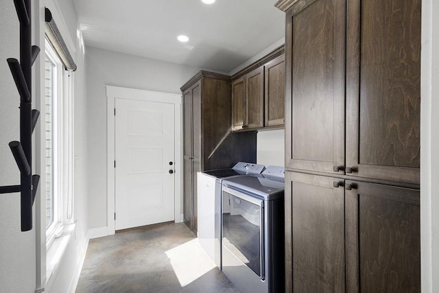 clothes washing area featuring separate washer and dryer and cabinets