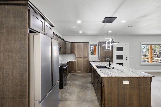 kitchen with sink, hanging light fixtures, an island with sink, stainless steel appliances, and light stone countertops