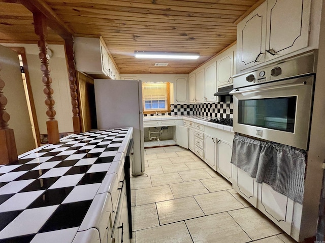 kitchen featuring stainless steel oven, tile counters, backsplash, and wood ceiling