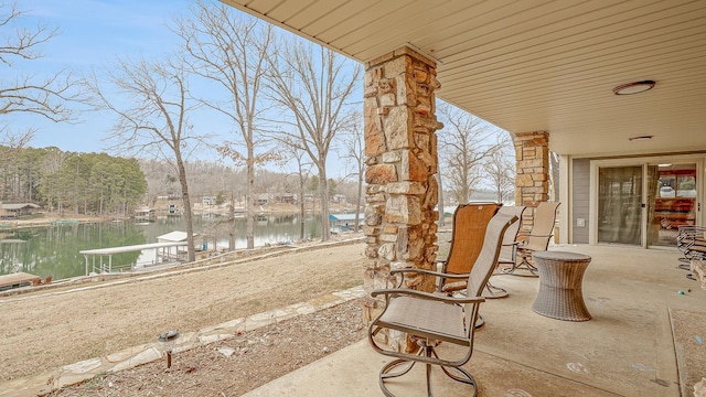 view of patio with a water view and a dock