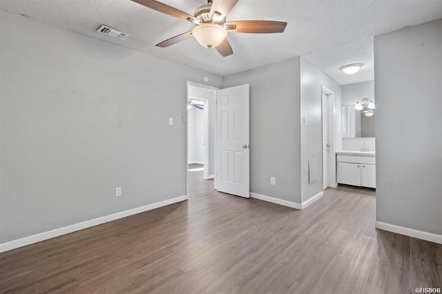 unfurnished bedroom with dark hardwood / wood-style flooring, ceiling fan, ensuite bath, and a textured ceiling