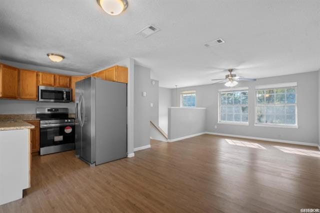 kitchen featuring ceiling fan, appliances with stainless steel finishes, and light hardwood / wood-style floors