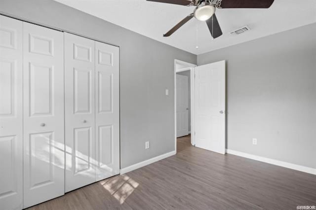 unfurnished bedroom with dark wood-type flooring, a closet, and ceiling fan