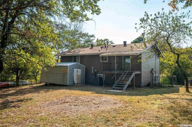 rear view of property with cooling unit, a storage shed, and a yard