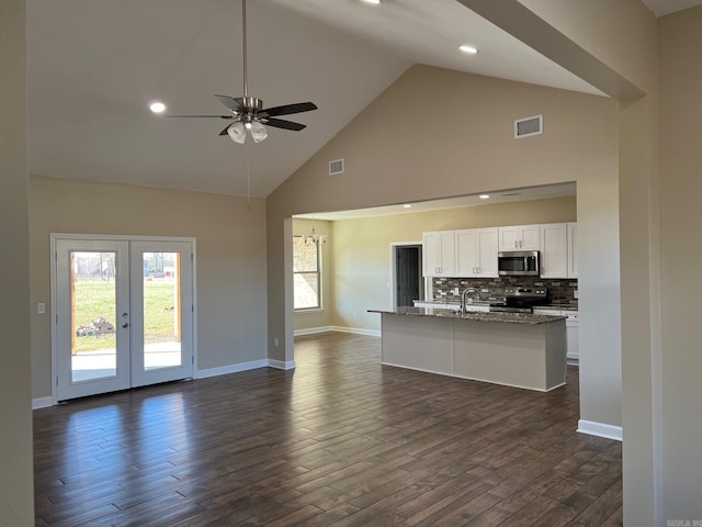 kitchen with dark wood-type flooring, white cabinetry, dark stone countertops, appliances with stainless steel finishes, and a wealth of natural light