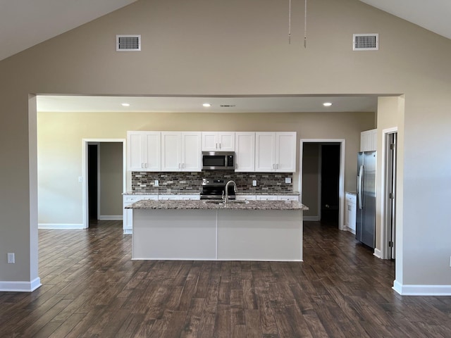 kitchen featuring light stone counters, a center island with sink, white cabinets, and appliances with stainless steel finishes