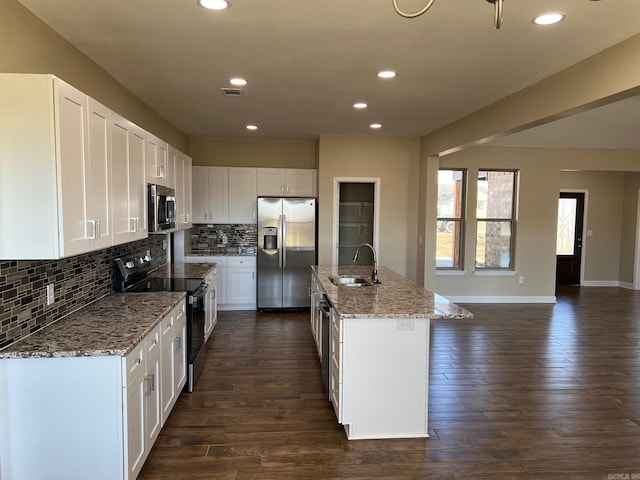 kitchen with sink, white cabinets, a kitchen island with sink, light stone counters, and stainless steel appliances