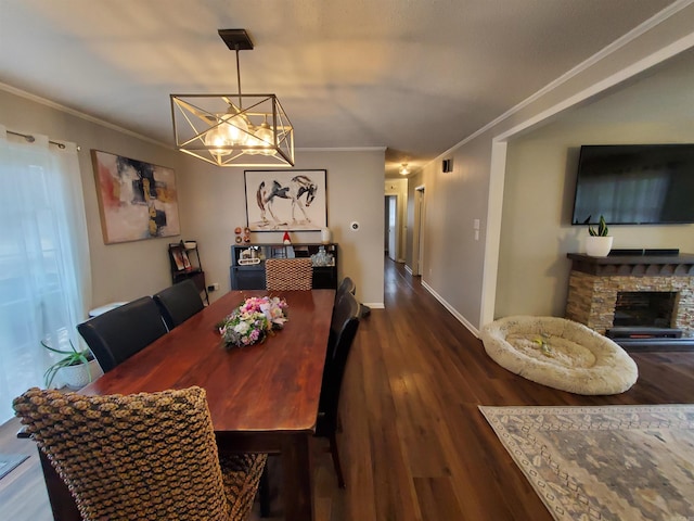 dining area with crown molding, a fireplace, dark wood-type flooring, and a notable chandelier