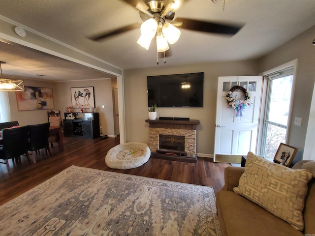 living room with a stone fireplace, dark wood-type flooring, and ceiling fan