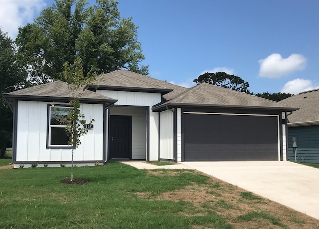 view of front of home with board and batten siding, concrete driveway, a front yard, roof with shingles, and a garage