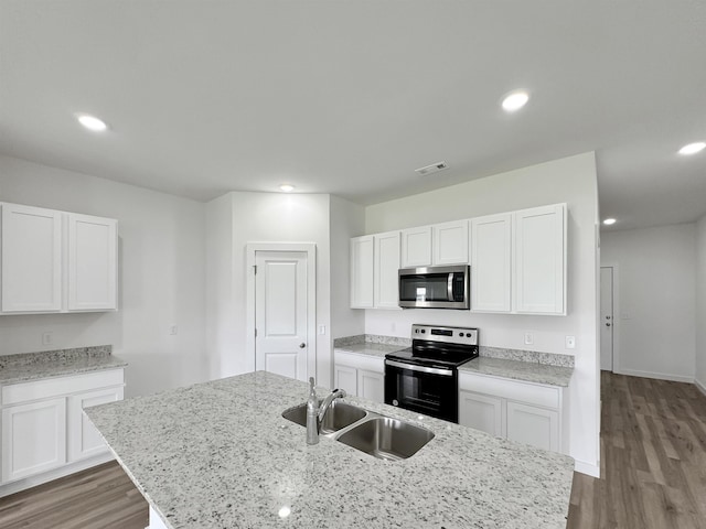 kitchen with sink, light hardwood / wood-style flooring, electric range oven, white cabinets, and a center island with sink