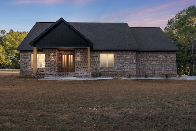 back house at dusk featuring a lawn