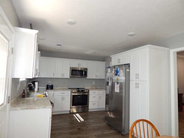 kitchen with sink, dark wood-type flooring, white cabinets, and appliances with stainless steel finishes