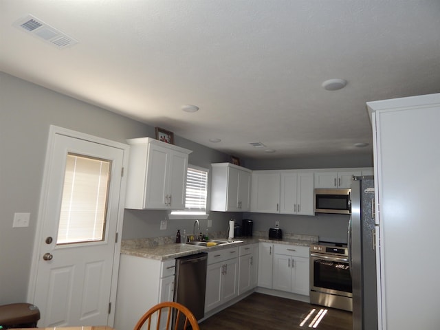 kitchen with sink, dark hardwood / wood-style floors, white cabinets, and appliances with stainless steel finishes