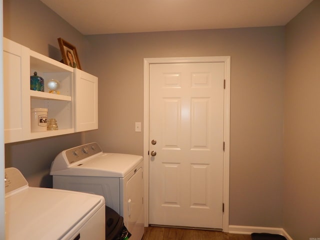 clothes washing area with cabinets, dark wood-type flooring, and washer and dryer