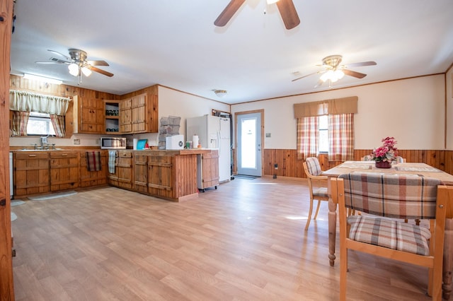 kitchen with white fridge with ice dispenser, wood walls, light wood-type flooring, and kitchen peninsula