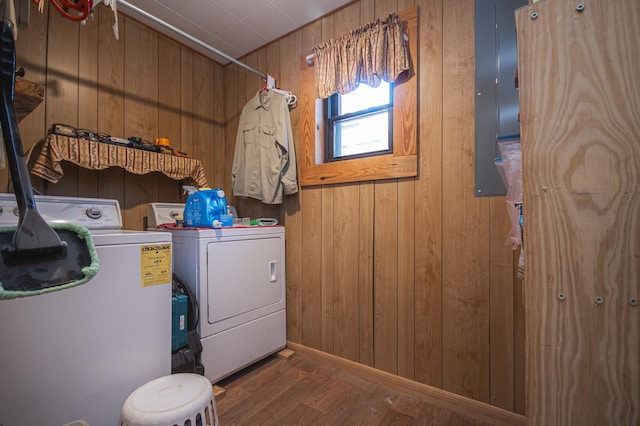 clothes washing area featuring dark wood-type flooring, washing machine and dryer, and wood walls