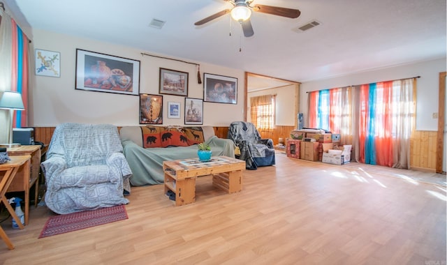 interior space featuring ceiling fan, wooden walls, and light wood-type flooring