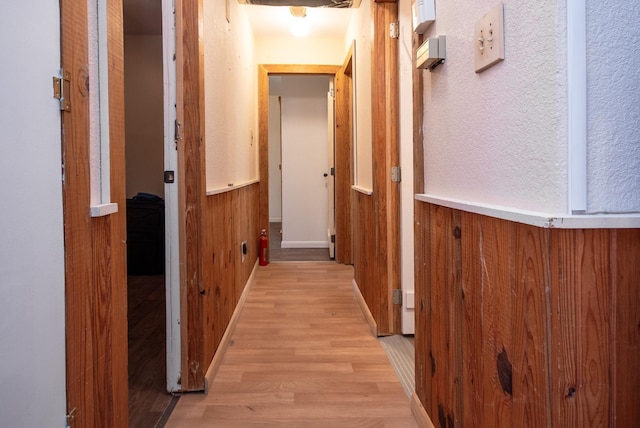 hall featuring wooden walls and light hardwood / wood-style flooring