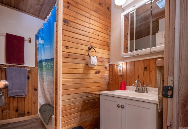 bathroom featuring vanity, hardwood / wood-style floors, shower / bath combo with shower curtain, and wood walls