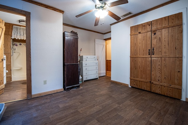 unfurnished bedroom featuring crown molding, dark wood-type flooring, ensuite bath, and ceiling fan