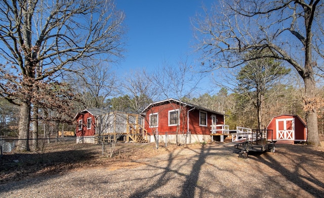 view of side of home with a wooden deck and a storage shed