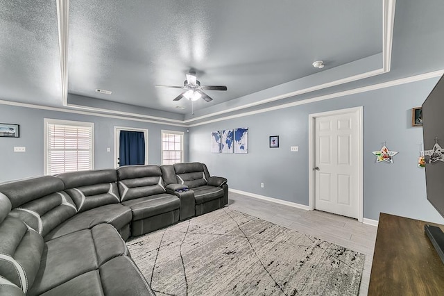 living room with light hardwood / wood-style flooring, ornamental molding, a raised ceiling, and ceiling fan