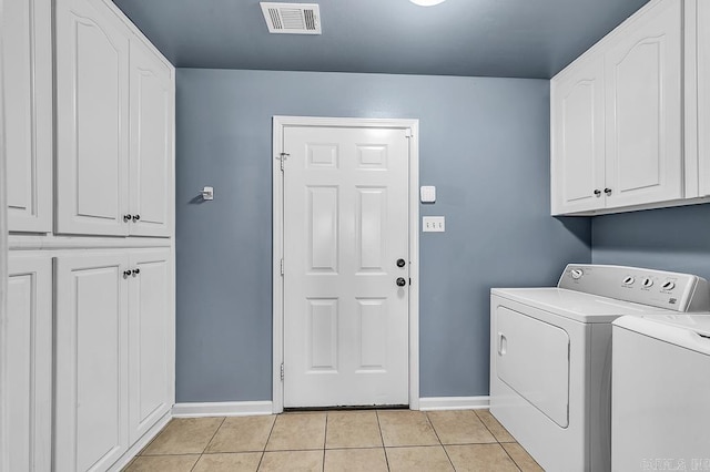 laundry room featuring cabinets, light tile patterned floors, and washing machine and clothes dryer