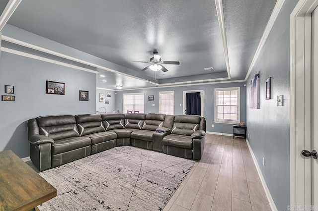 living room with ceiling fan, hardwood / wood-style floors, ornamental molding, a textured ceiling, and a raised ceiling