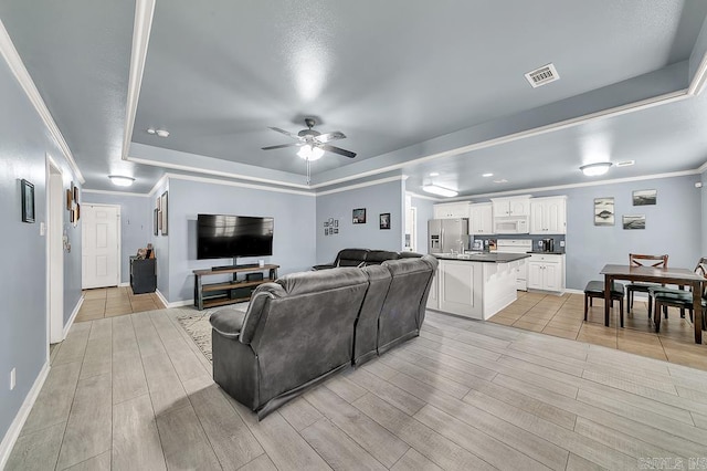 living room featuring crown molding, a tray ceiling, and ceiling fan