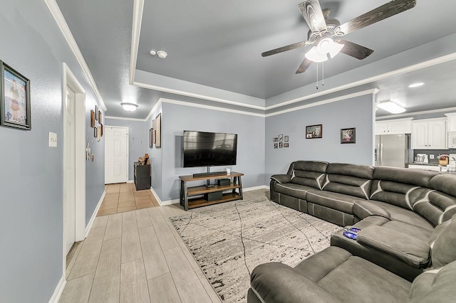 living room featuring a tray ceiling, ornamental molding, and ceiling fan