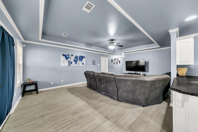 living room featuring light hardwood / wood-style floors, a raised ceiling, and ceiling fan