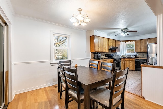 dining space featuring ornamental molding, ceiling fan with notable chandelier, a textured ceiling, and light wood-type flooring