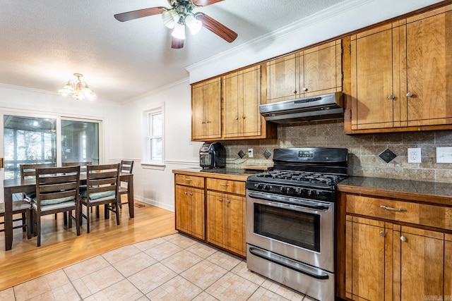 kitchen featuring gas range, ornamental molding, a textured ceiling, and decorative backsplash