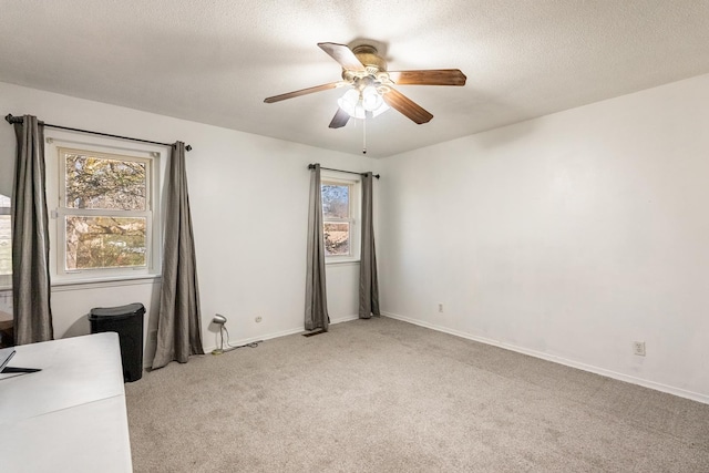 carpeted spare room with plenty of natural light, a textured ceiling, and ceiling fan