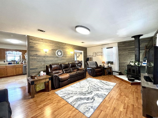 living room featuring wood walls, a wood stove, and light wood-type flooring